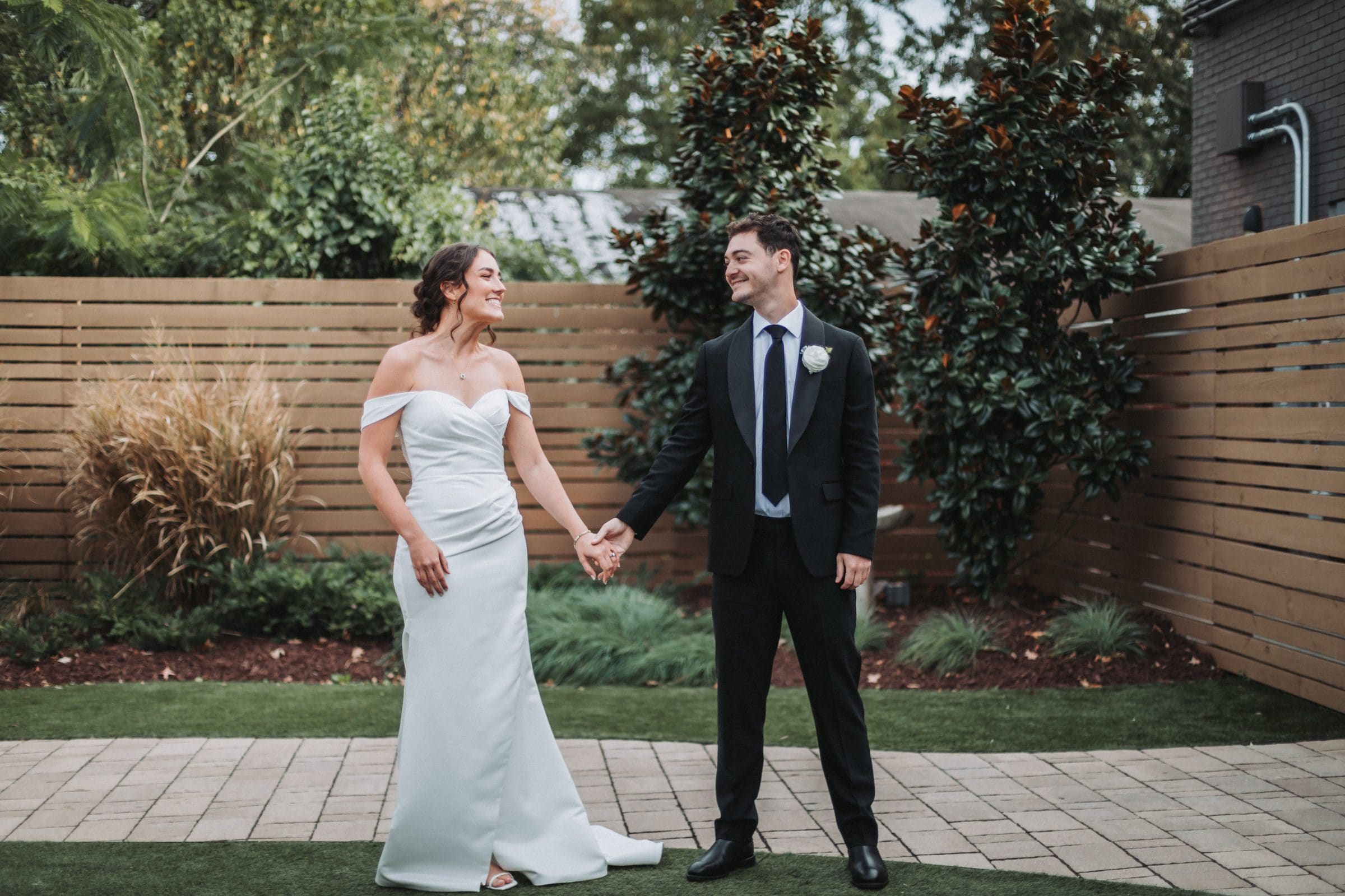A couple holding hands in a garden on their wedding day